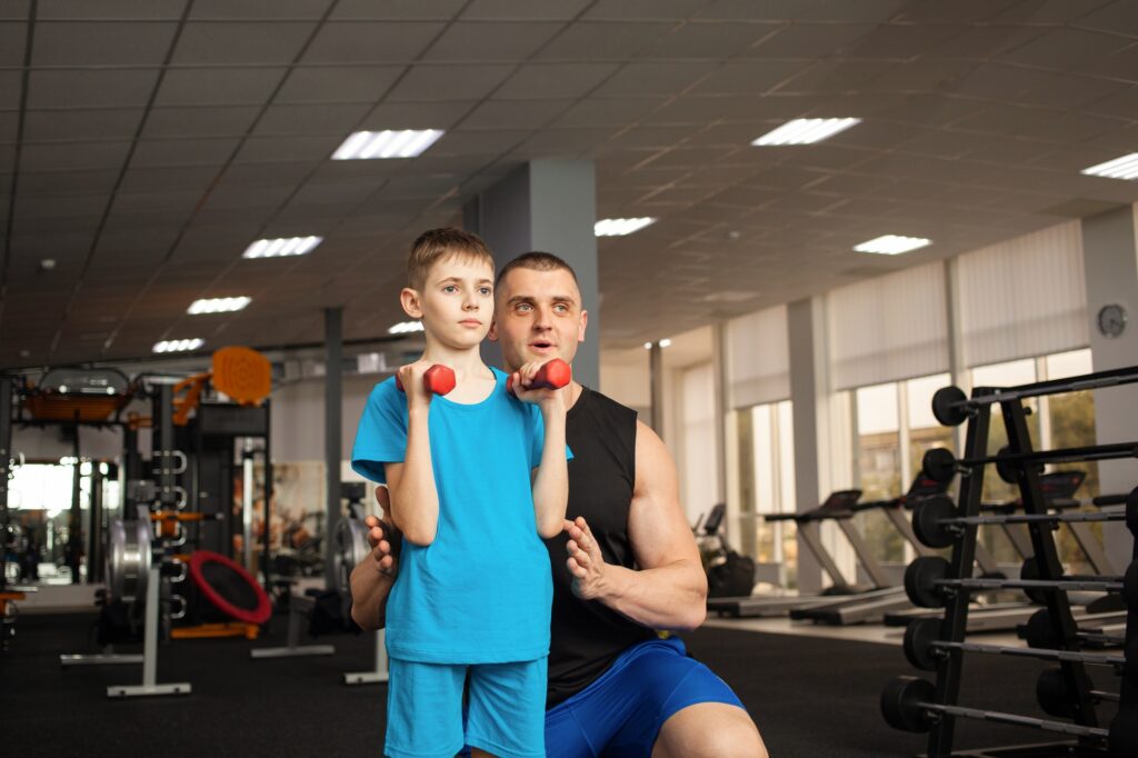 child performs an exercise with dumbbells with a trainer